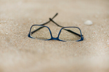 Fototapeta na wymiar Blue rimmed glasses on the sand.