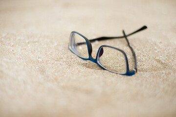 Fototapeta na wymiar Blue rimmed glasses on the sand.