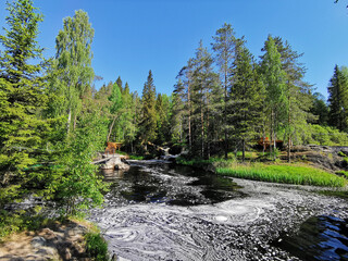 A picturesque waterfall on the Tokhmayoki River in Karelia surrounded by trees on a clear summer...