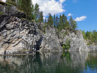 An adit in the steep slope of a flooded Marble Canyon in the Ruskeala Mountain Park on a sunny summer day.