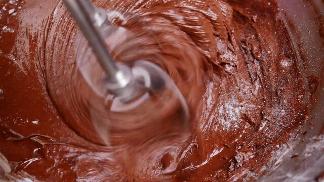 Close up of mixing flour, melted chocolate and cocoa powder in bowl with an electric mixer. Step by step recipe of making homemade Delicious chocolate cookies or brownie cake.