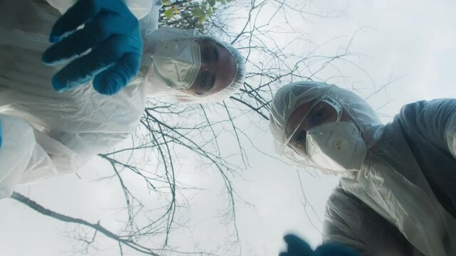 People wearing ppe white suits showing with fingers and arguing. Medical examiners working near accident place. Chemical danger, nature researching. 
