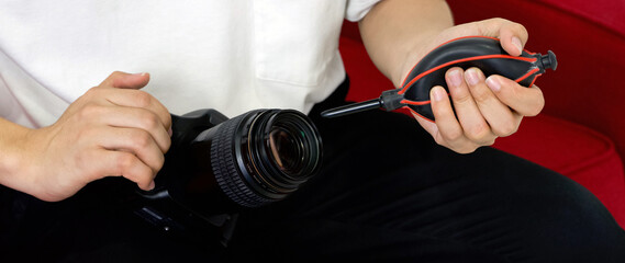 Young photographer cleaning the camera and lens with a air blower camera cleaning after shooting...