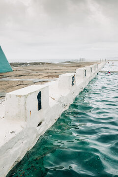 vertical shot of empty diving block stands with numbers in an ocean pool on a cloudy day