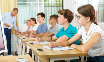 Fototapeta na wymiar Pupils sitting in class and listening carefully to male teacher.