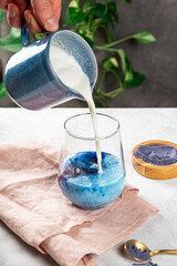 Making latte from blue matcha tea, new trendy superfood healthy food, vertical photo