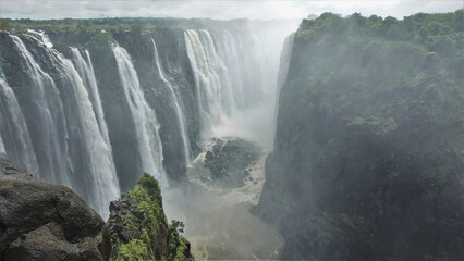 Powerful streams of water descend into the gorge. At the bottom of the abyss is a stormy river,...