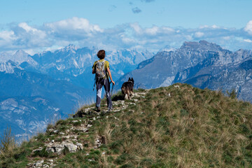 hiker in the mountains with his dog. mountain ridge landscape with blue sky - obrazy, fototapety, plakaty