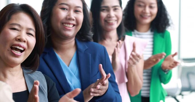 Businesswomen group in business clothes set row and clapping hands together give applause, appreciated and support sign for someone. Idea of good team work and strong relationship in modern office.