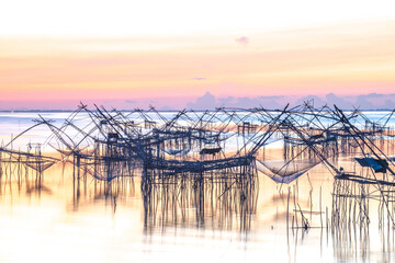 Silhouette traditional equipment asia fishing net on sunrise in Pak Pra Village, Phatthalung, Thailand.