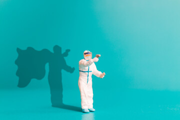 Obraz premium Miniature people Doctor with superhero shadow on the wall. Hospital staff heroes concept