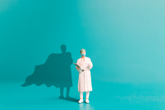 Miniature people Doctor with superhero shadow on the wall. Hospital staff heroes concept