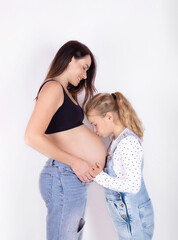 A child kisses the stomach of his pregnant mother. The anticipation of motherhood