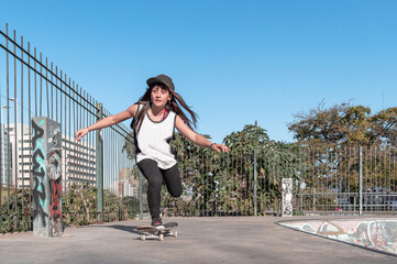 young white latin skater girl on skateboard riding on the ramp at the skate park