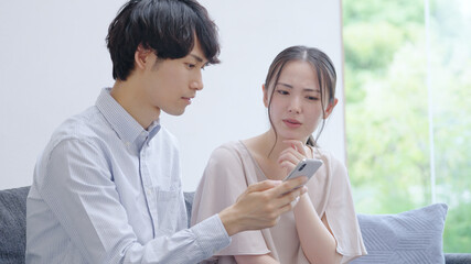 スマホを見る若い夫婦・カップル