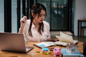 Architect woman hand-draw a design house with a model on a wooden desk. Property idea in real...