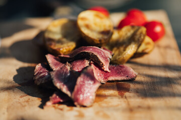 Cutting medium rare grilled tenderloin steak on a wooden board