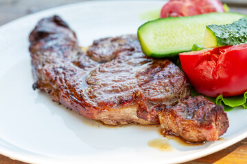 Beef steak with vegetables on a white plate.   Selective focus