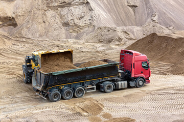 Obraz premium A loader loads sand into the car body in a sand quarry