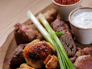 Grilled meat assorted mix beef kebab and chicken mix on wooden plate with sauce. Rustic dinner style. Selective focus, Top flat view