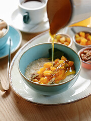 Bowl with oatmeal and diet fruits, berries, nuts and honey. Home heathy breakfast food concept with natural sun light