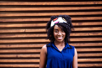 Portrait of a young happy black woman against wooden background.