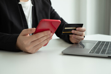 The businesswomen's hand is holding a credit card and using a smartphone for online shopping and internet payment in the office