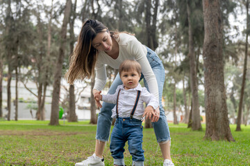Fototapeta premium Mother helping her son to walk in an urban park