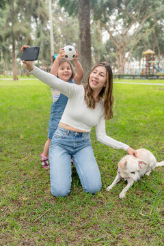 Mother taking a selfie with the mobile with her daughter and a dog