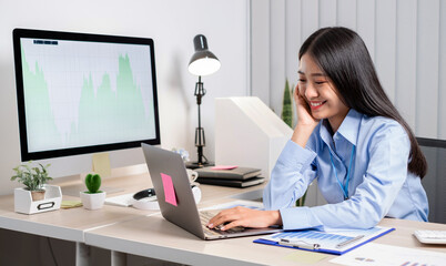 Fototapeta na wymiar Asian woman working on a laptop with a cheerful and happy smile while working at the office