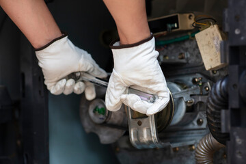 Selective focus hands of auto mechanic are using the wrench to repair home electic machine