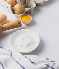 Flour and eggs, rolling pin on grey background.Baking and cooking ingredients.  Soft selective focus.