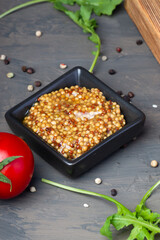 French mustard in a triangular saucepan on a dark table with a concrete texture. the concept of...