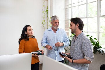 Three people standing, collaborating in an open office