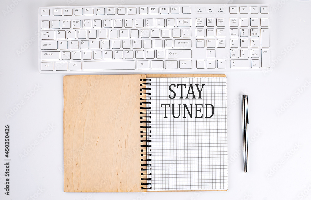 Poster stay tuned text on the notebook with keyboard on the white background