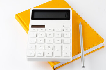 Yellow notebook with a pencil and a calculator on a white background - Powered by Adobe