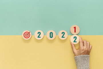 Hand slid wooden cube with the number 2021 to 2022 on yellow and green background. Happy new year...