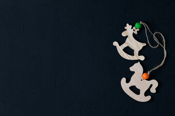 Banner Top view with Christmas toys and decorations on a dark background. Wooden toy deer and horse for Christmas tree. The concept of a New Year's holiday. Space for the text. flat lay