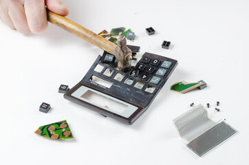 Nervous, irritated man smashes calculator with hammer. His hand hits the plastic casing of the...