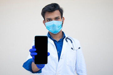 Doctor Holding Mobile Phone Against Plain Background