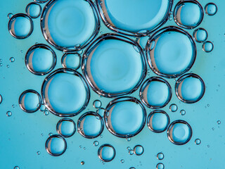 Closeup of oil drops motion on water surface. Colorful abstract macro background of oil drops on water surface with air bubbles inside