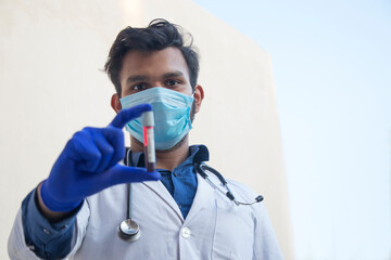 Fototapeta na wymiar A doctor wearing face mask analyzing a blood sample