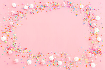 Party colorful candies and meringue over pastel pink background. Top view, flat lay