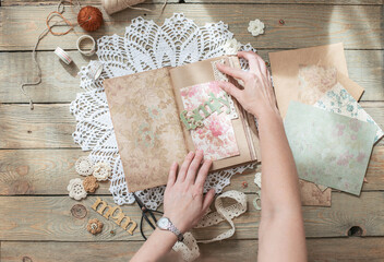 Scrapbooking. On a wooden background, a girl makes a photo album for a family in a vintage style.