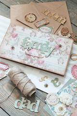 Scrapbooking. On a wooden background, a girl makes a photo album for a family in a vintage style.