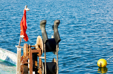 Deck of a wooden fishing boat with rubber fisherman boots on the capstan.