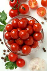 Bowl with pickled tomatoes and ingredients on white background