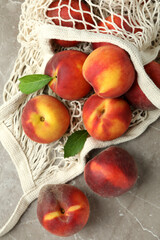 String bag with peach fruits on gray textured table