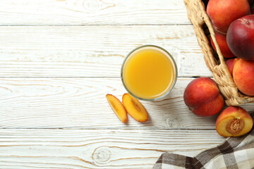 Glass of peach juice and peach fruits on white wooden table