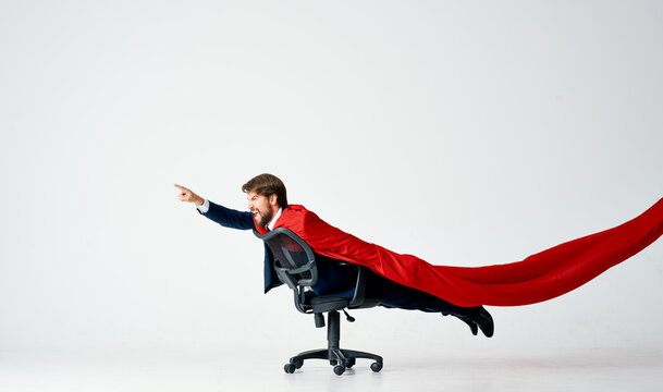 a man in a suit with a red cloak rides in a superman chair